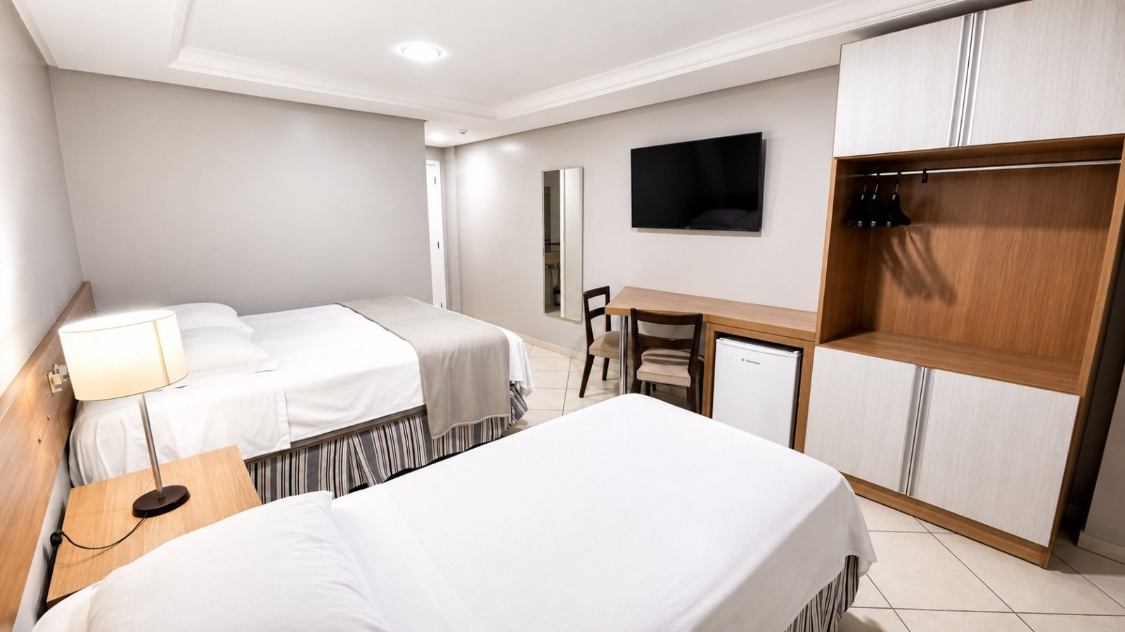 Quarto Super Luxo do Treville Hotel Carazinho com cama Queen Size, TV e armário amplo
